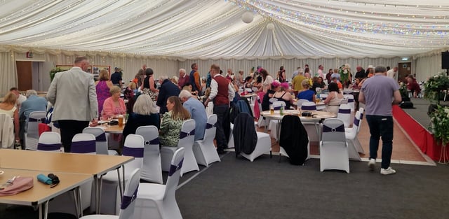 Guests gathered around tables in a decorated function room.