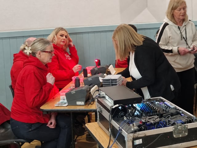 Adults at the betting table, with ticket equipment and the audio mixer in the foreground.